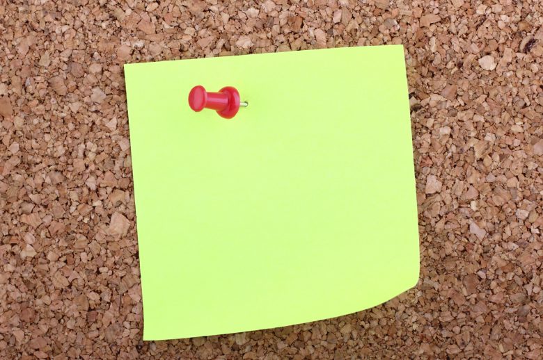 A blank sticky note on a cork board