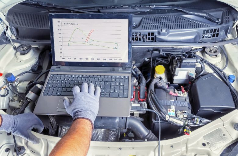 An auto mechanic runs a diagnostic scan on a car engine