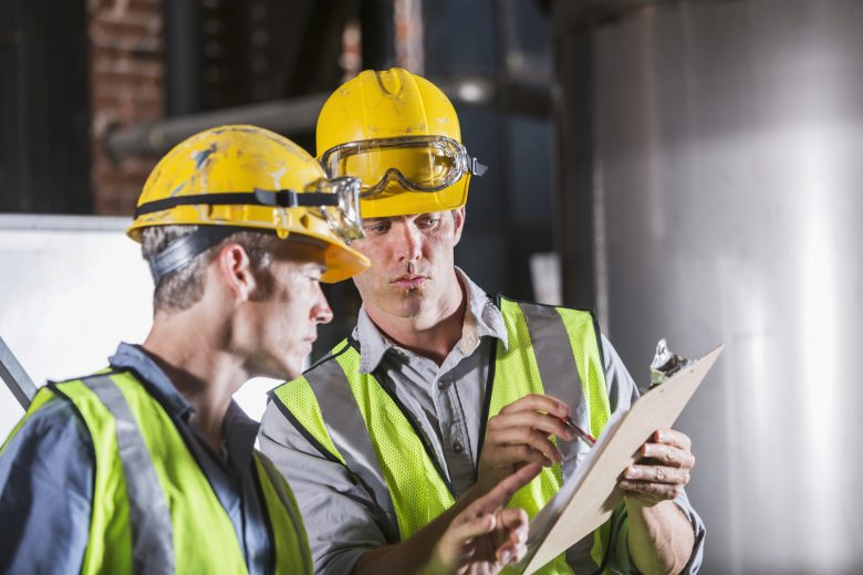 Two workers consult a safety checklist