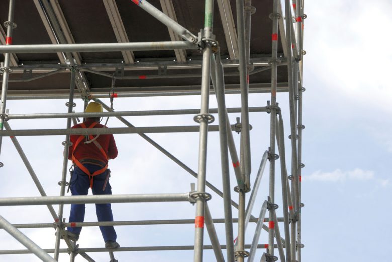 Construction worker tied off using scaffolding