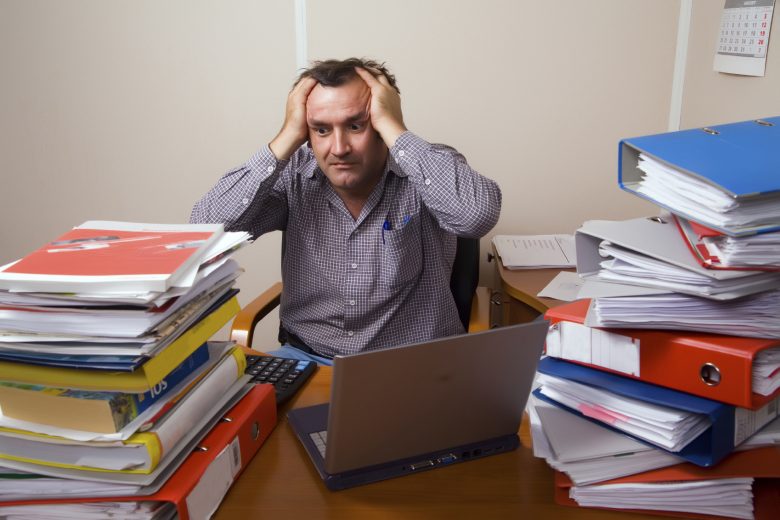 Man stressed with multiple binders surrounding him