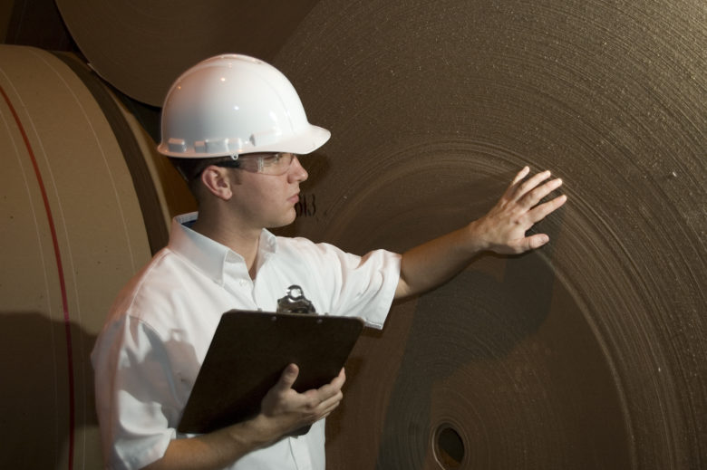 An engineer or Inspector checks a new roll of paper at a paper mill.