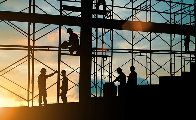 Silhouette of construction team working safely on scaffolding on high rise building.