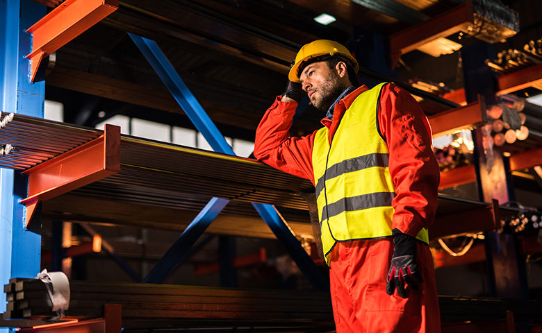 Pensive metal worker standing in aluminum mill.