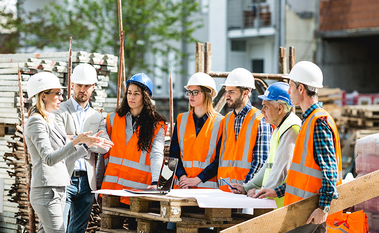 Construction workers gathered around listening to a toolbox talk