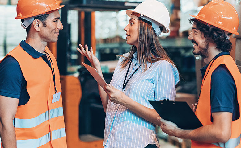 Warehouse workers talking to their manager in front of forklift