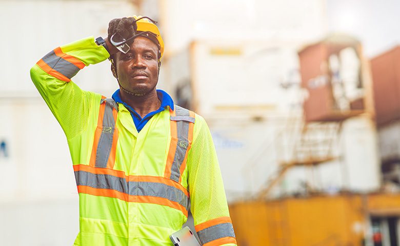 Tired stress worker sweat from hot weather in summer working in port goods cargo shipping logistic ground, Black African race people.