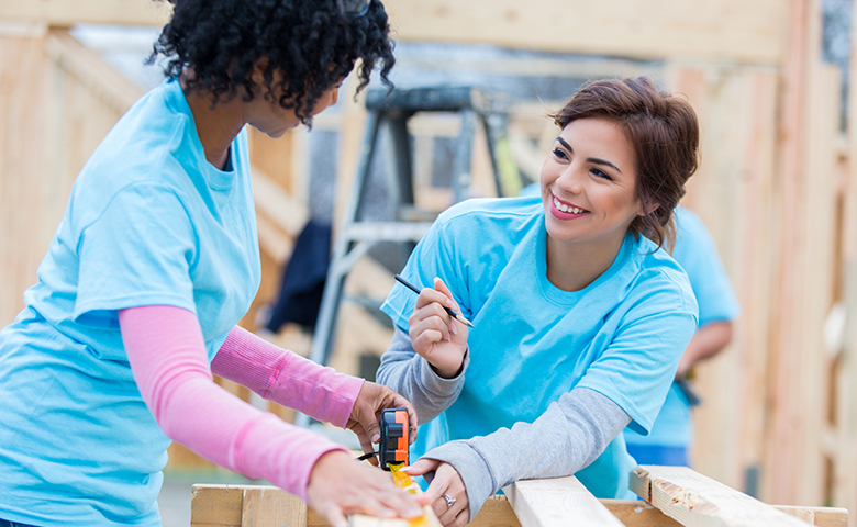 Female volunteers talk while working on charity home