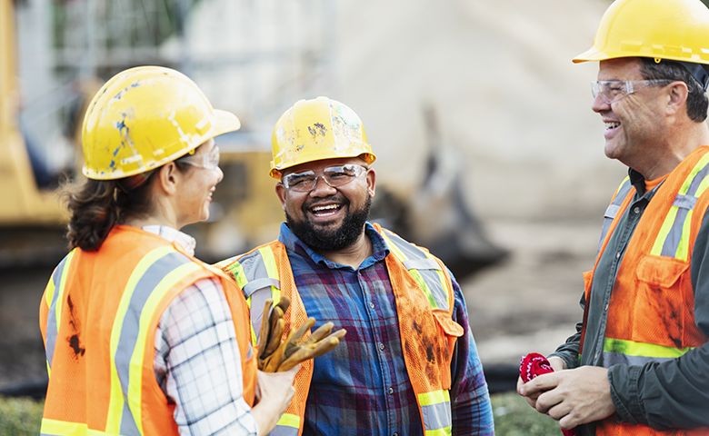 Three happy engaged construction workers chatting